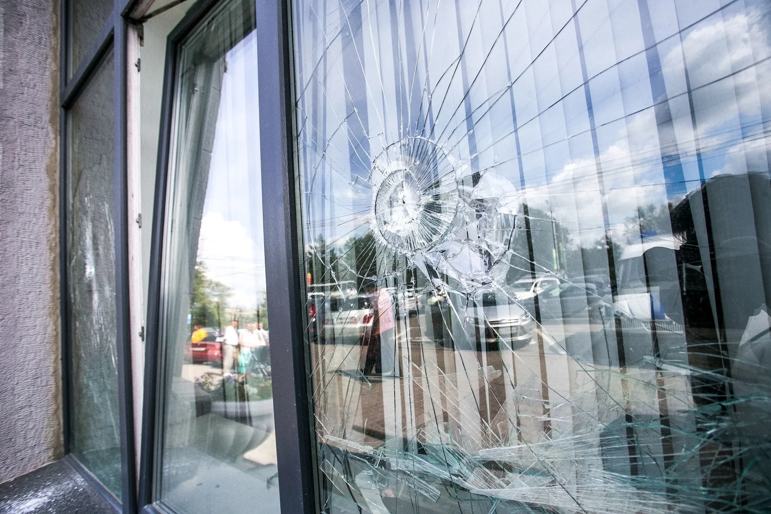 Damaged shop window with a large visible crack caused by an impact.