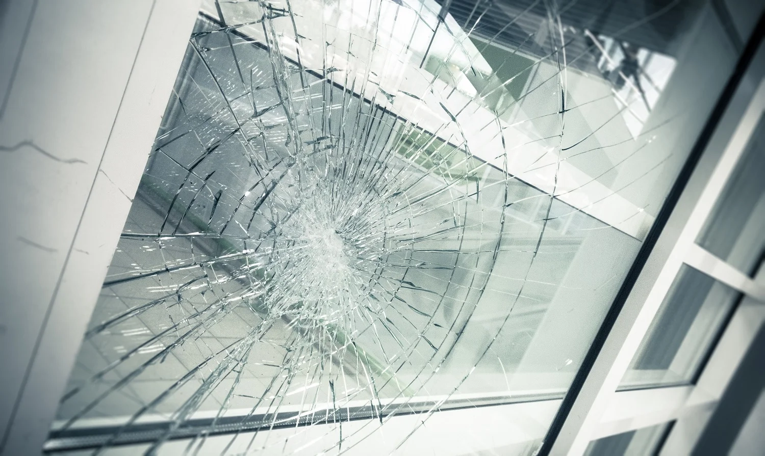 Severely shattered glass window with impact damage